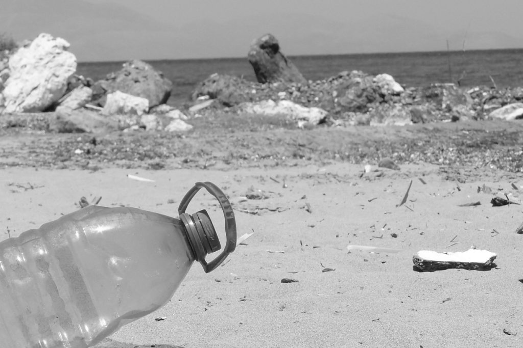 Una botella de plástico de desecho tirada en la playa (blanco y negro)