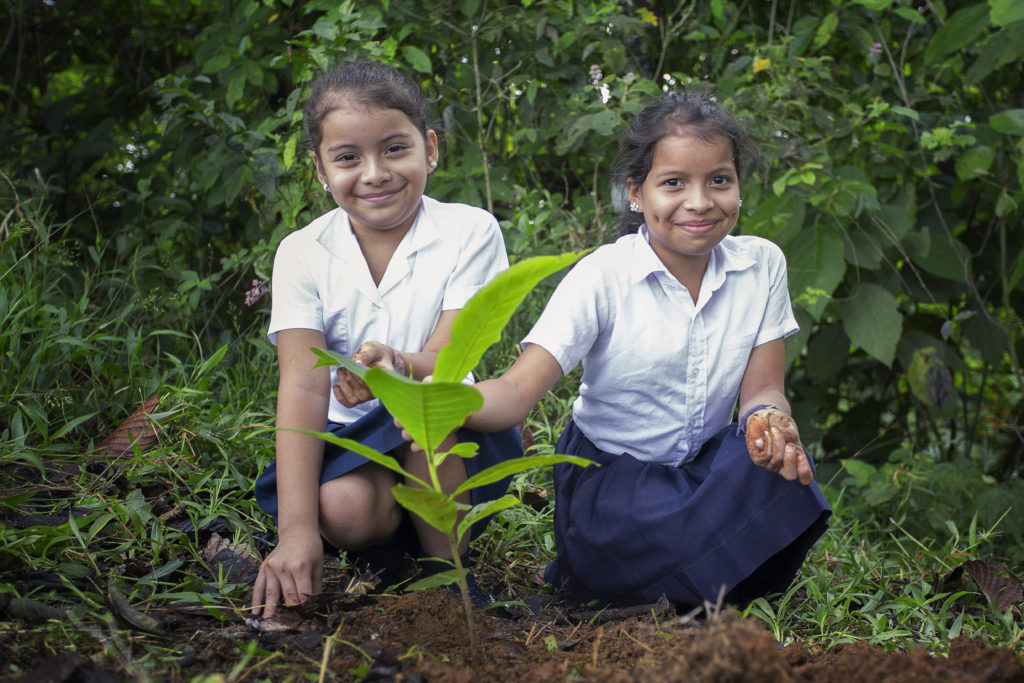 zwei Schulmädchen die einen Baum in Costa Rica pflanzen